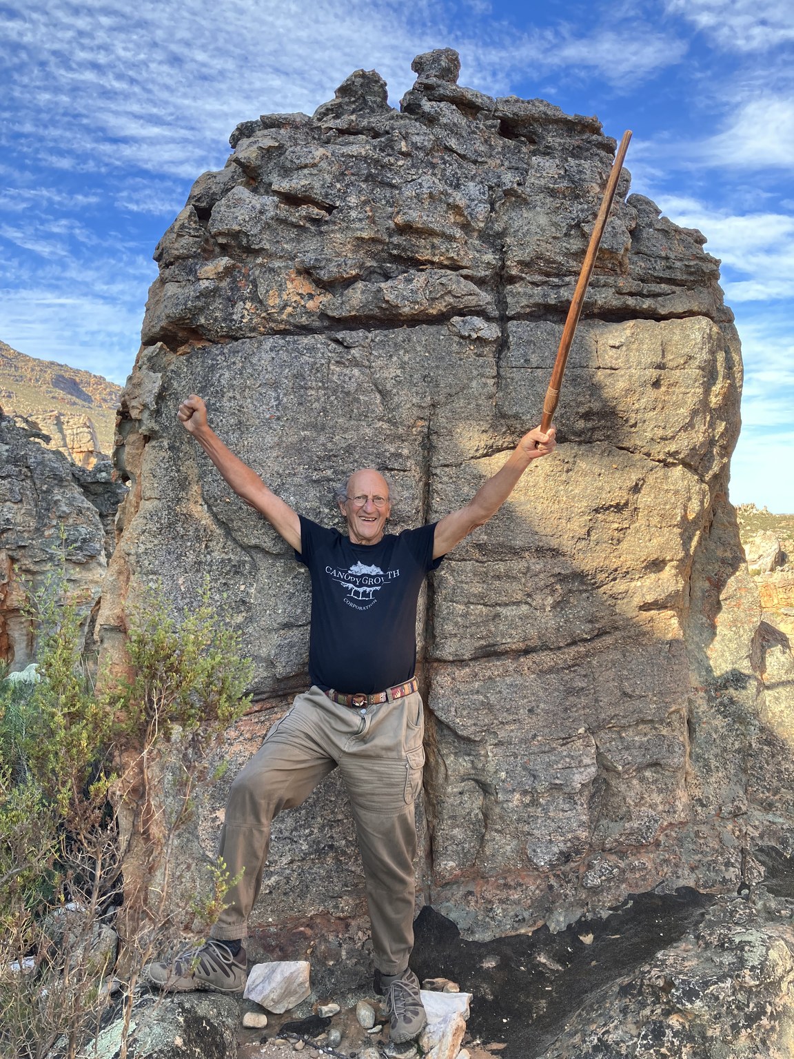 Dr Bernard Brom, arms raised in delight at the foot of a Cederberg rock face